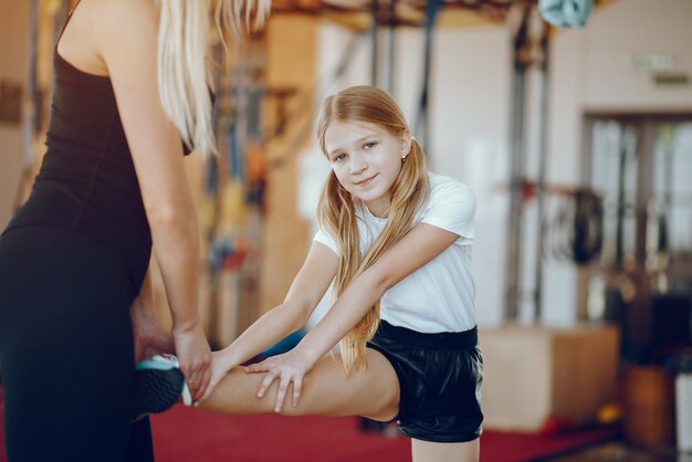 Mother with cute daughter play sports in the gym