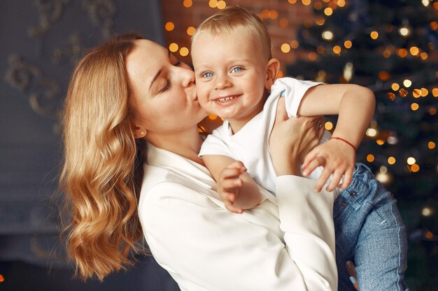 クリスマスツリーの近くに家でかわいい息子を持つ母