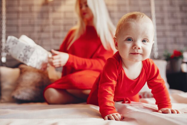 Mother with cute son sitting on a bed at home