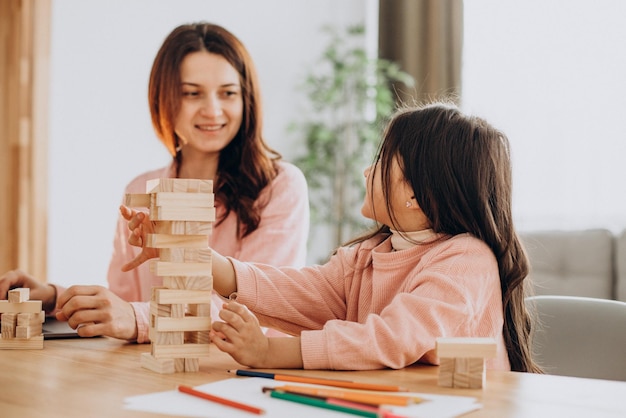 Madre con figlia che costruisce blocchi di legno jenga nella torre