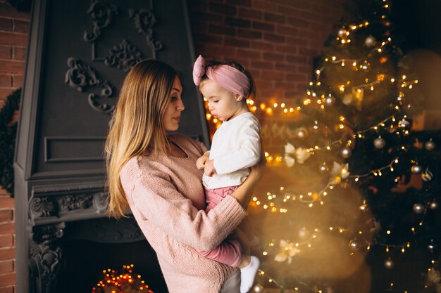 Mother with daughter by Christmas tree