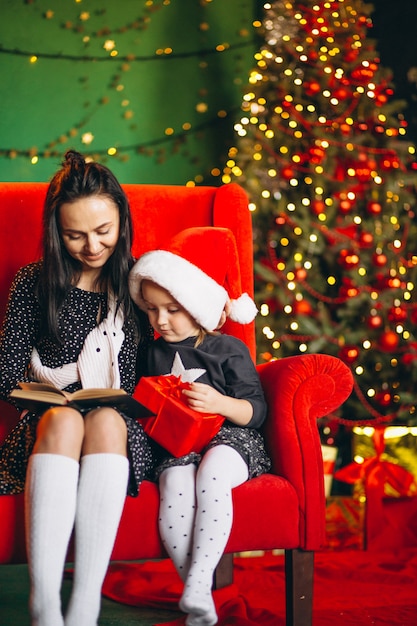 Mother with daughter on Christmas sitting on sofa with presents