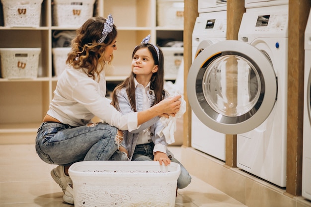 Free photo mother with daughter doing laundry at self serviece laundrette