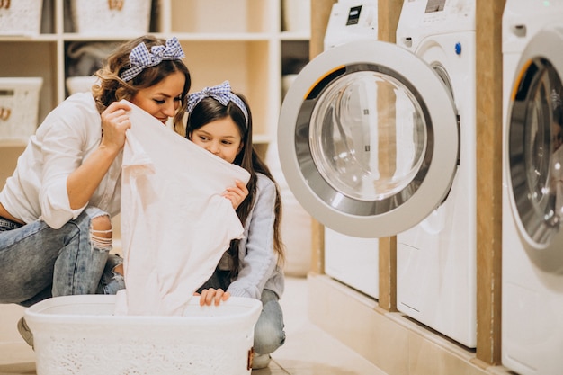 Mother with daughter doing laundry at self serviece laundrette