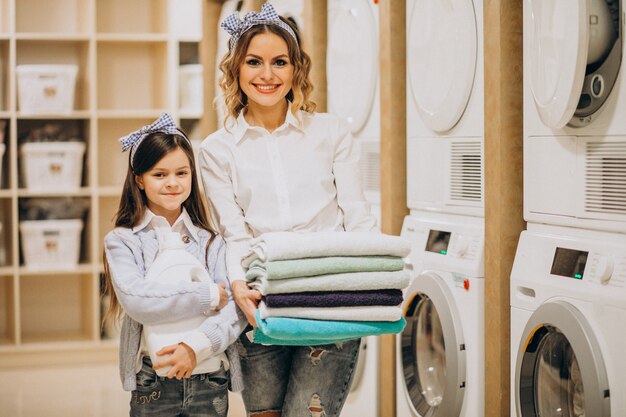 Mother with daughter doing laundry at self serviece laundrette