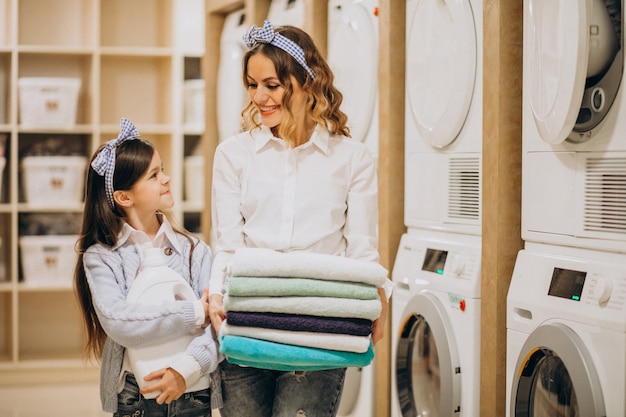 Foto gratuita madre con la figlia che fa lavanderia alla lavanderia automatica del self service