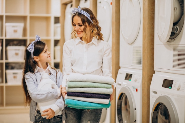 Mother with daughter doing laundry at self serviece laundrette