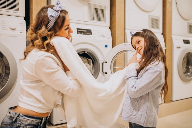 Mother with daughter doing laundry at self serviece laundrette