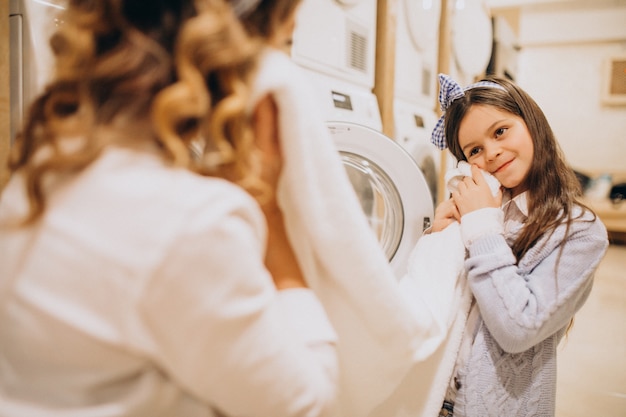 Foto gratuita madre con la figlia che fa lavanderia alla lavanderia automatica del self service