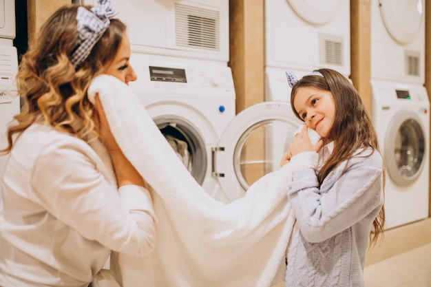 Foto gratuita madre con la figlia che fa lavanderia alla lavanderia automatica del self service