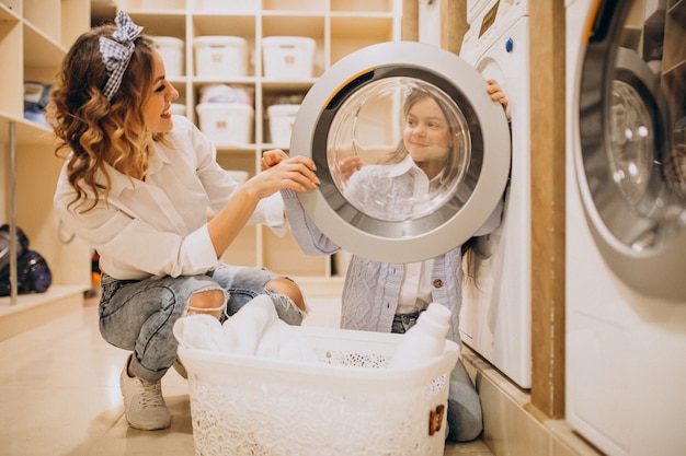 Madre con la figlia che fa lavanderia alla lavanderia automatica del self service