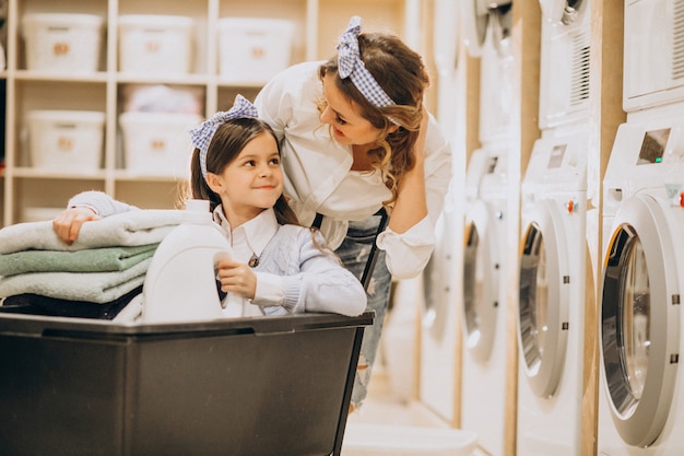 Madre con la figlia che fa lavanderia alla lavanderia automatica del self service