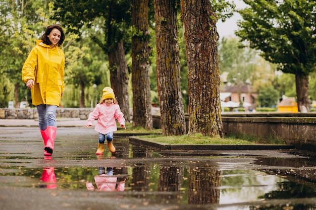 Mother with daughter having fun jumping in puddles