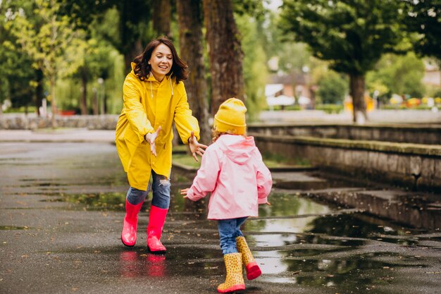 Mother with daughter having fun jumping in puddles