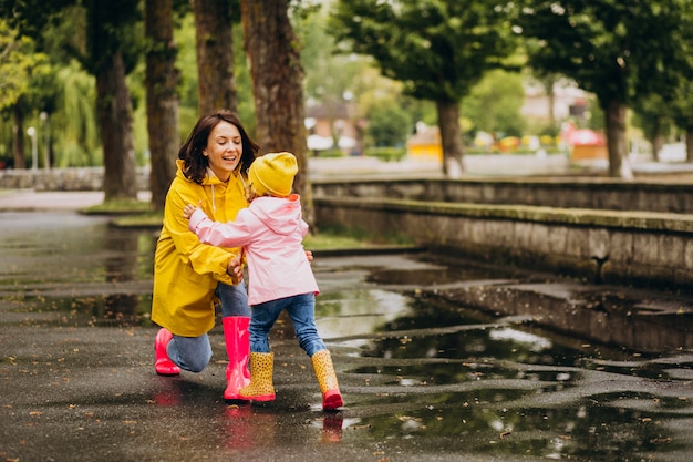 Mother with daughter having fun jumping in puddles