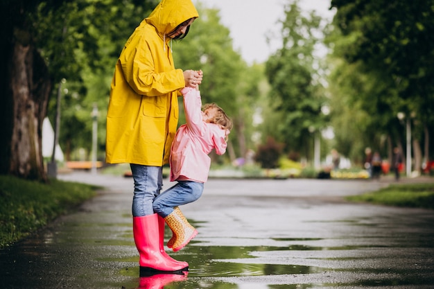 雨の日の公園で楽しんでいる娘を持つ母