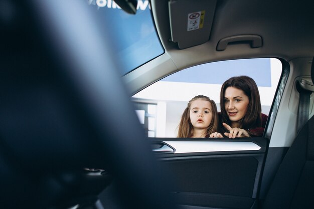 Mother with daughter looking inside a car in a car showroom