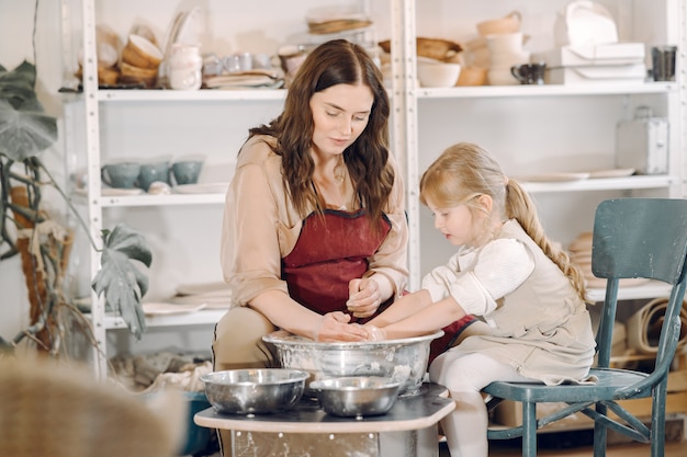 Mother with daughter makes vase in a potterystudio