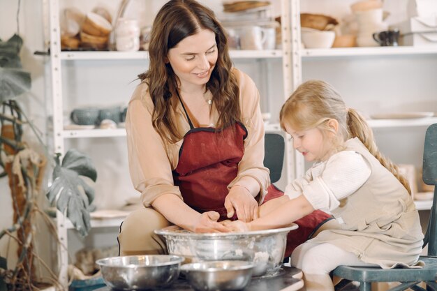 Mother with daughter makes vase in a potterystudio