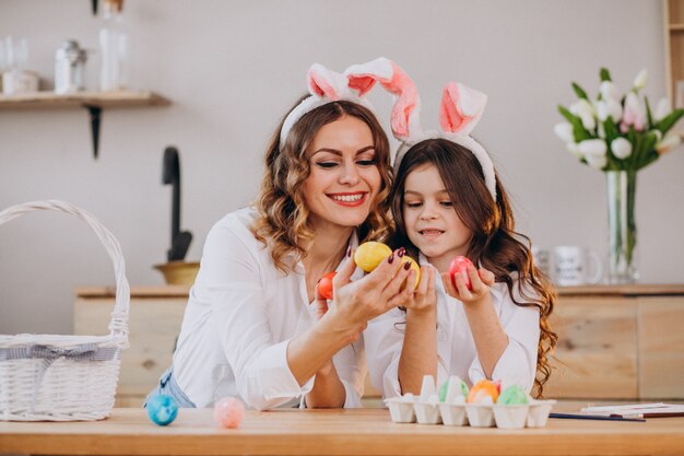 Mother with daughter painting eggs for easter