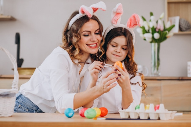 Mother with daughter painting eggs for easter