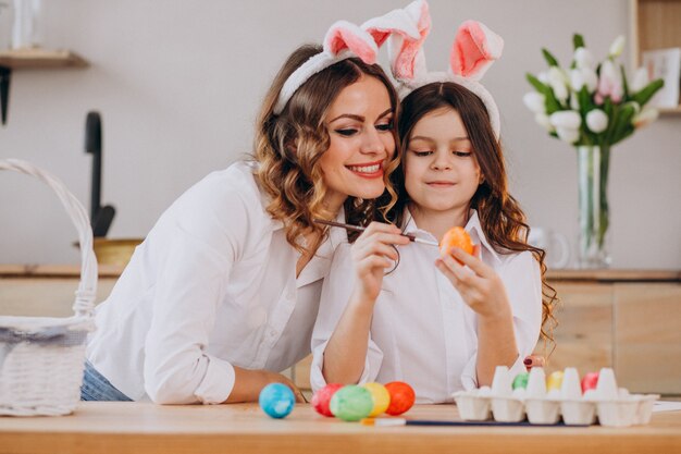 Mother with daughter painting eggs for easter