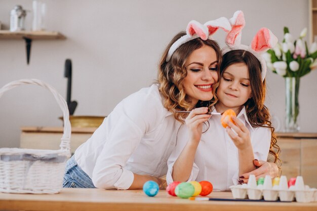 Mother with daughter painting eggs for easter