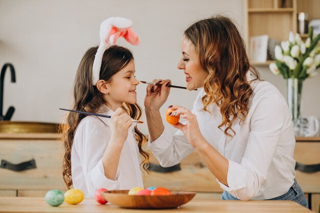 Mother with daughter painting eggs for easter