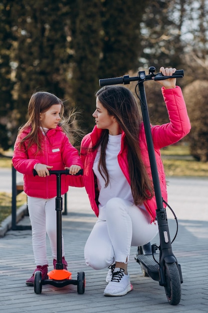 Mother with daughter riding electric scooter