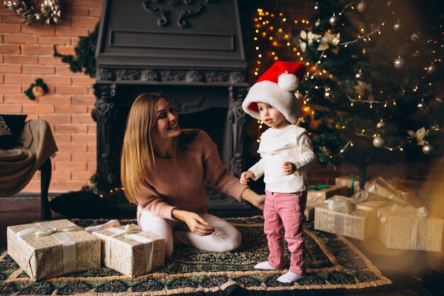 クリスマスツリーのそばに座って娘を持つ母