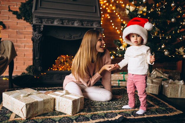 クリスマスツリーのそばに座って娘を持つ母