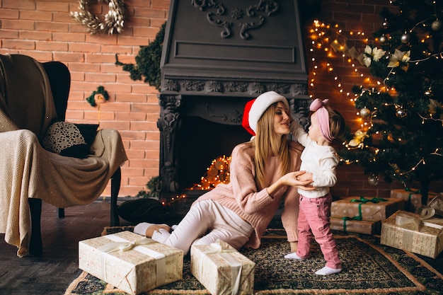 Mother with daughter sitting by Christmas tree