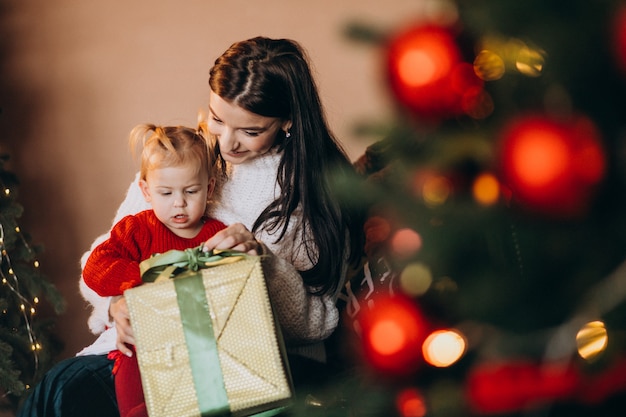 Mother with daughter sitting by the Christmas tree