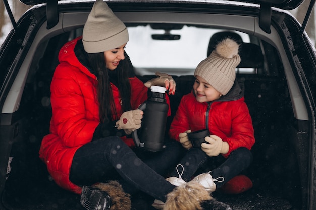 Mother with daughter sitting in car in winter