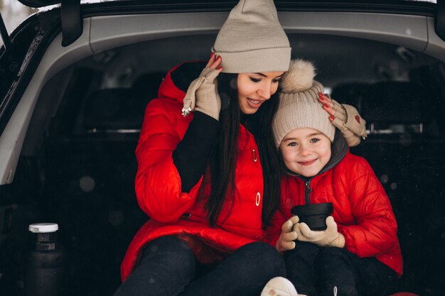 Mother with daughter sitting in car in winter