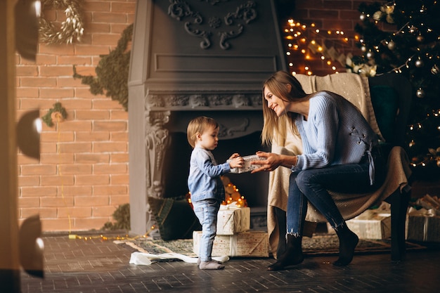 Mother with daughter sitting in chair by Christmas tree