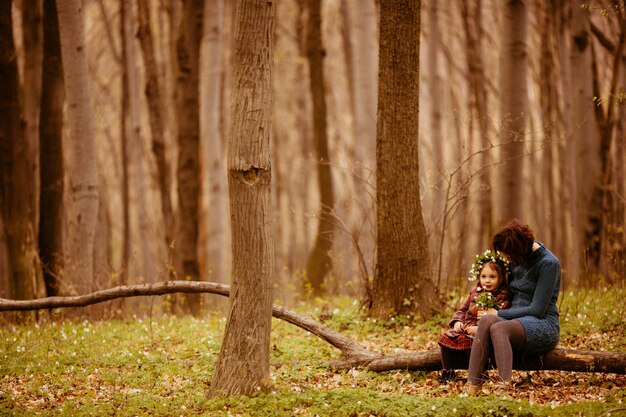 The mother with daughter sitting on the trunk 