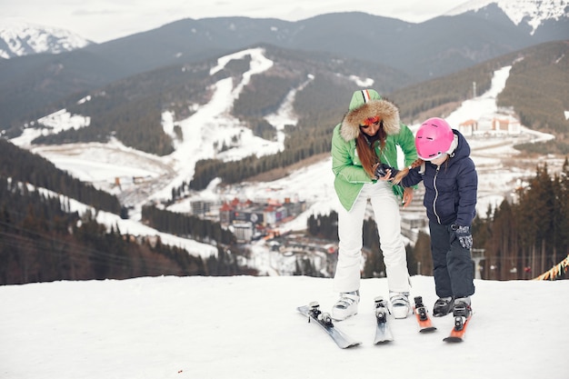 娘のスキーを持つ母。雪山の人々。