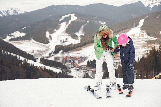 娘のスキーを持つ母。雪山の人々。