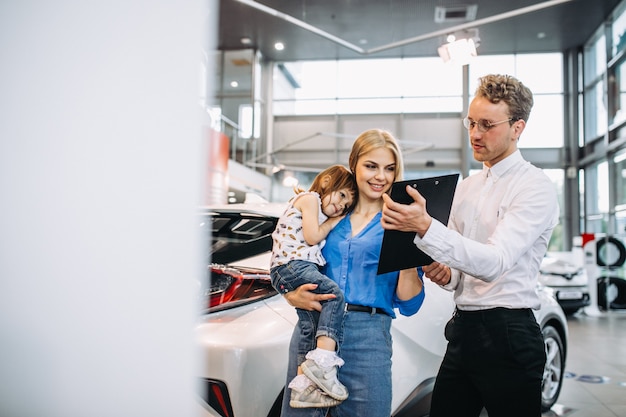 車のショールームで営業担当者に話している娘を持つ母