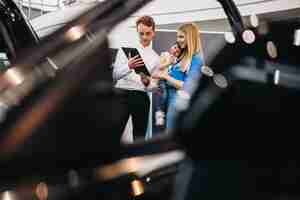 Free photo mother with daughter talking to sales person in a car showroom