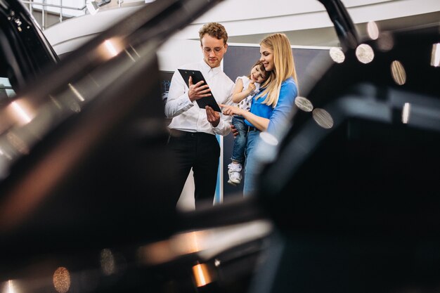 Mother with daughter talking to sales person in a car showroom