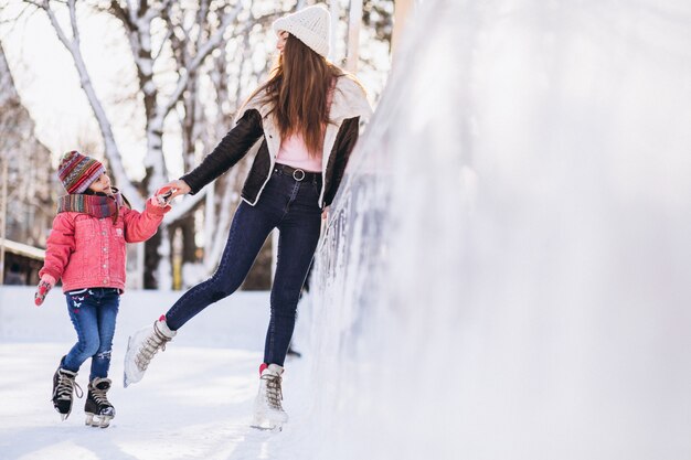 Mother with daughter teaching ice skating on a rink