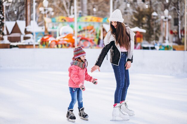 Мать с дочерью учат катанию на коньках на катке
