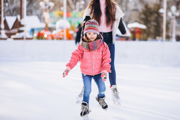 Free photo mother with daughter teaching ice skating on a rink