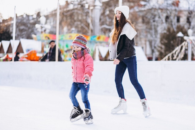 Mother with daughter teaching ice skating on a rink