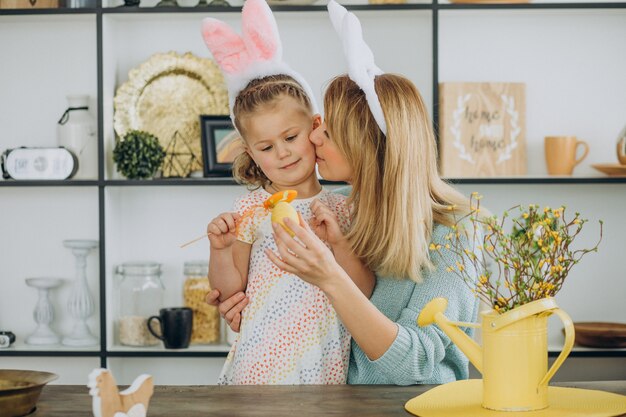 Mother with daughter together at the kitchen holding easter eggs