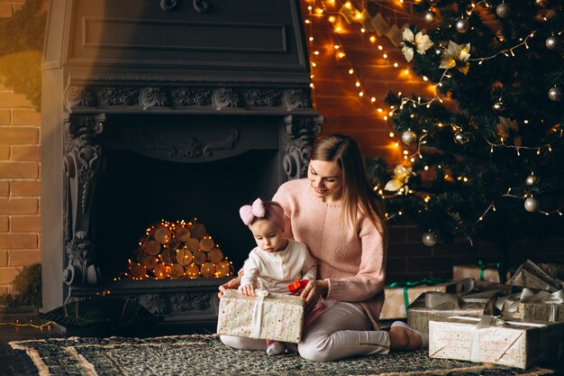 クリスマスツリーで開梱のクリスマスの娘を持つ母