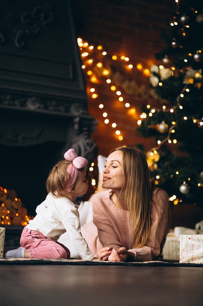 Mother with daughter unpacking christmas presents by Christmas tree