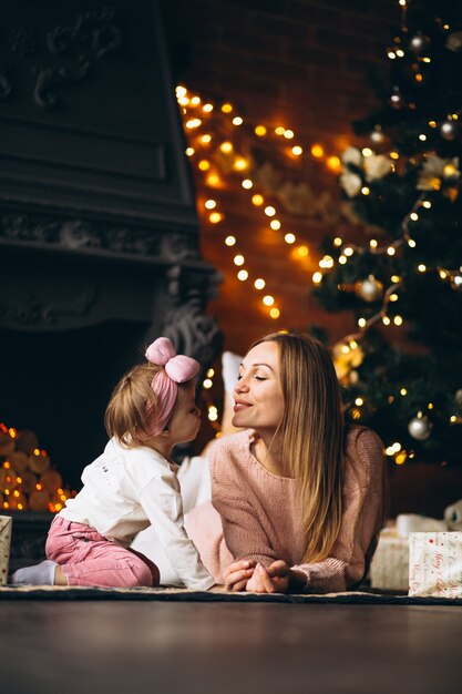 Mother with daughter unpacking christmas presents by Christmas tree